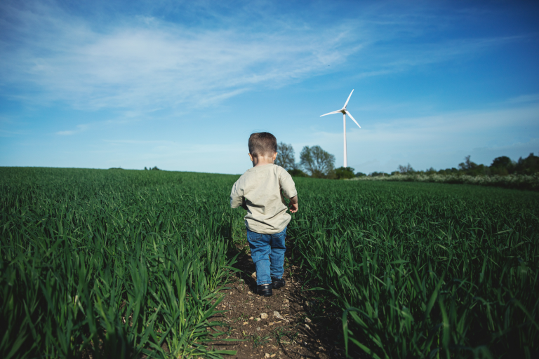 Foto van kindje in het veld met een windmolen
